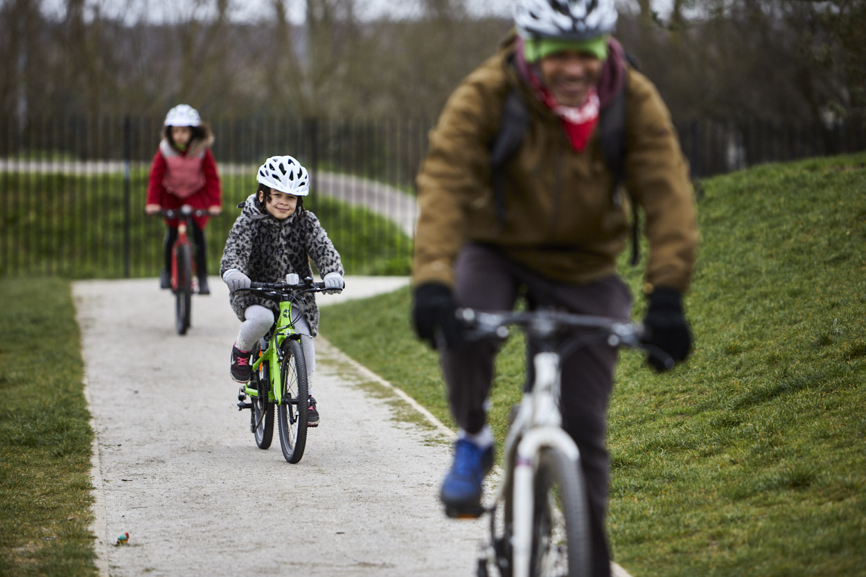 Family cycling across park