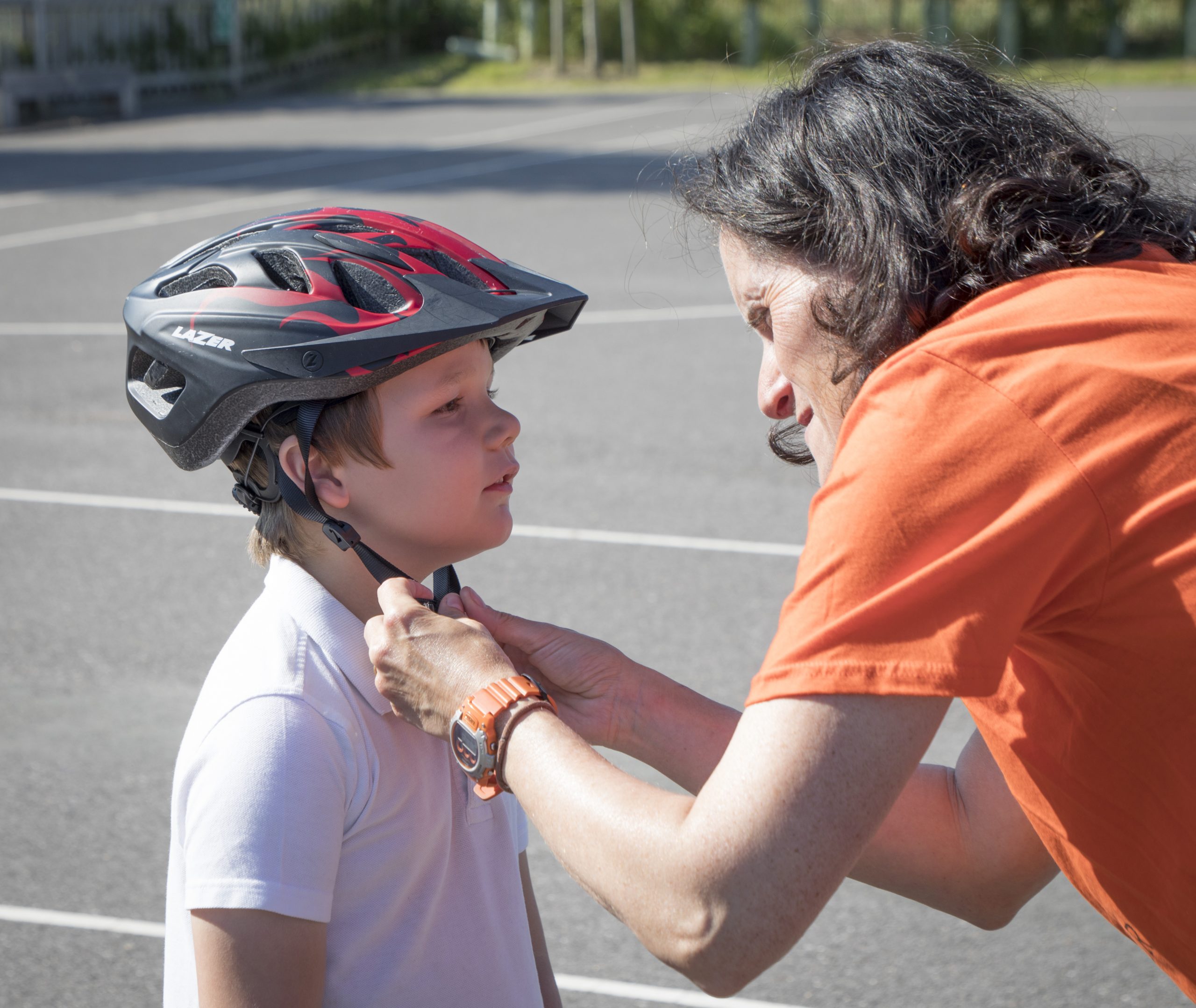 A woman puts a cycle helmet on a boy