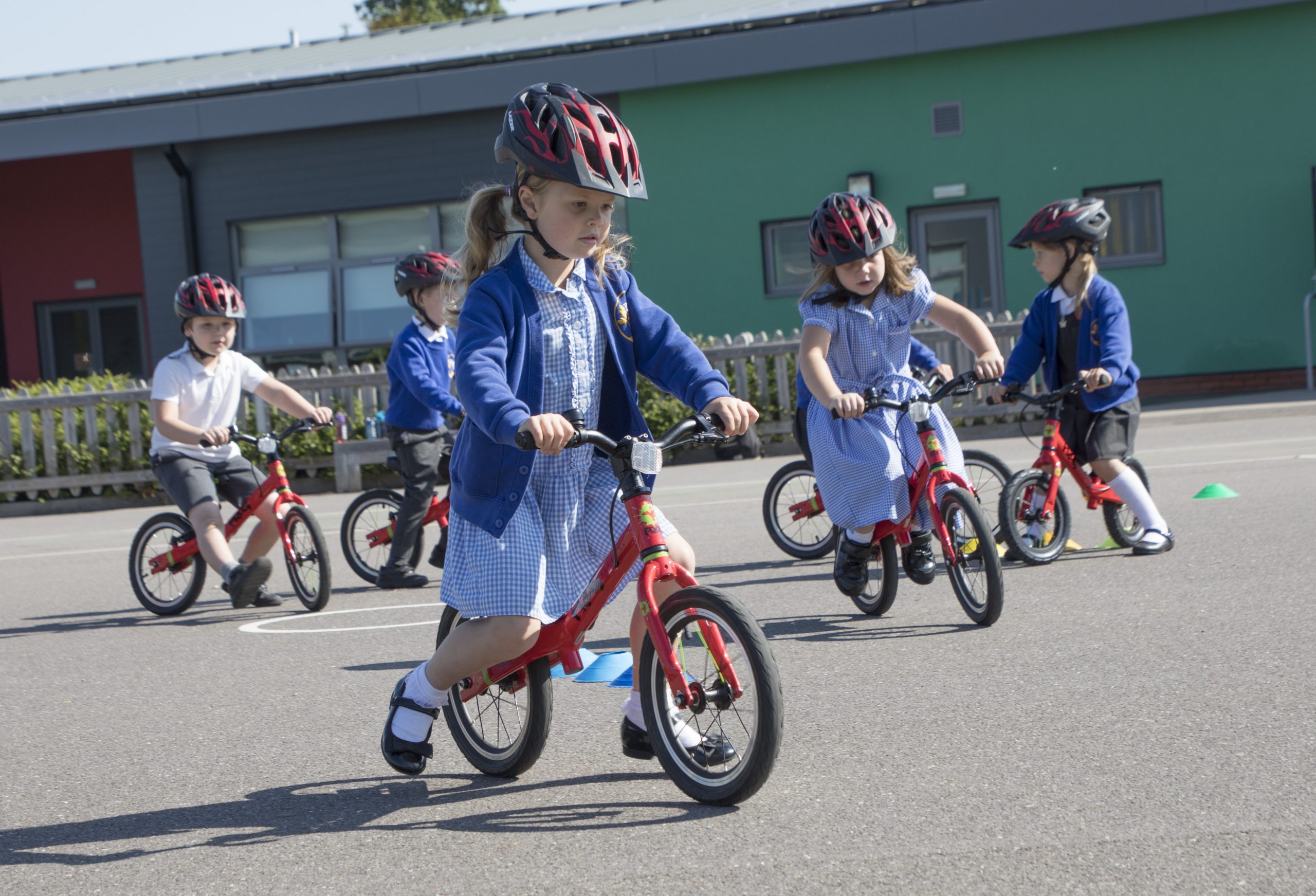 Young children in school uniform riding balance bikes