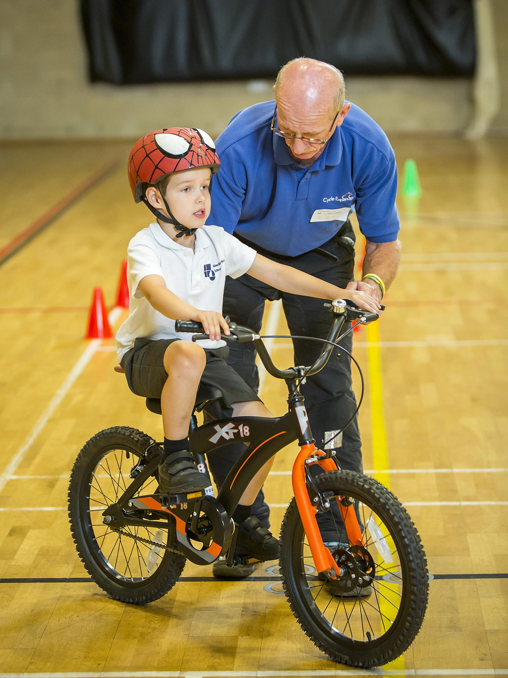 A man teaches a boy how to ride a bike